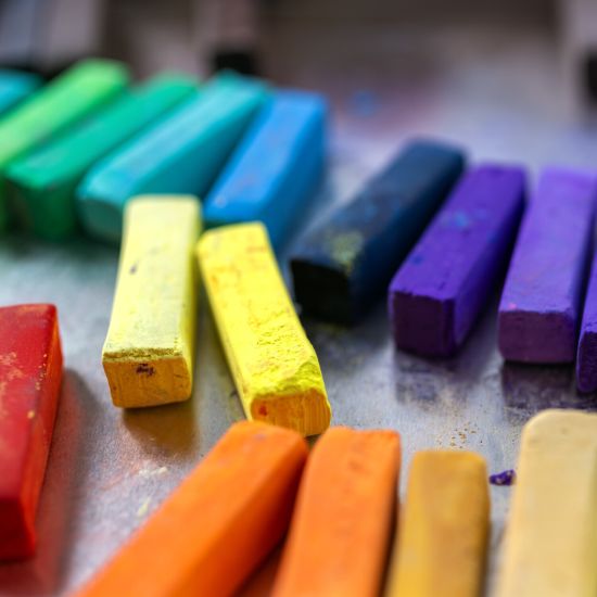 Close-up of colourful crayons on a bench.