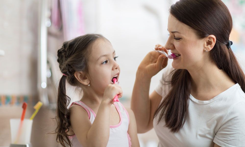 Mother and daughter brushing teeth